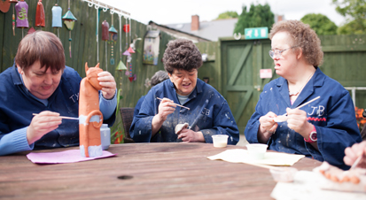 Three people painting pottery.