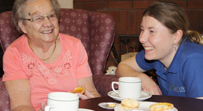 Two people laughing over a cup of tea.